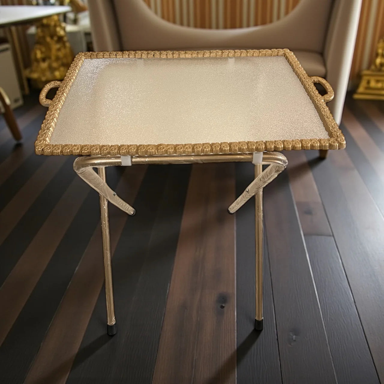 Decorative tray with gold frame and beige surface on a wooden floor